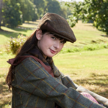 Woman wearing Blooms of Autumn silk scarf with a flat cap and plaid coat in a park setting