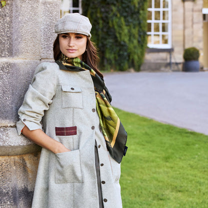 Woman in tweed coat and cap with By the Castle Gate silk scarf around neck.