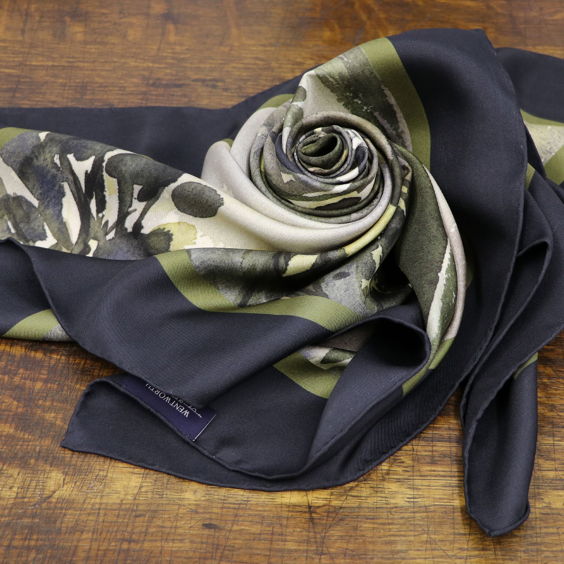 Where the Salmon Leap silk scarf folded into a rose shown on wooden table | Silk Scarf | Wentworth of Yorkshire